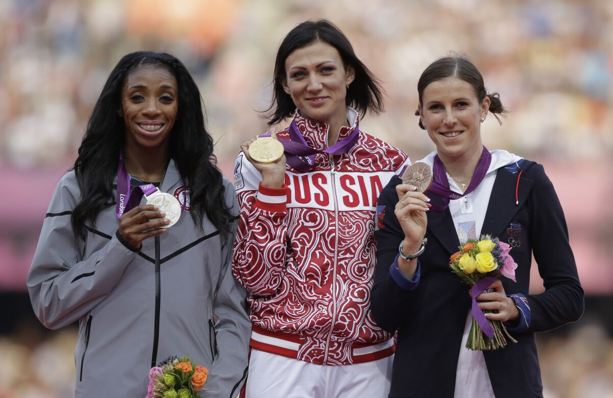 ARCHIVO - La rusa Natalya Antyukh (medio) sostiene su medalla de oro junto a la estadounidense Lashinda