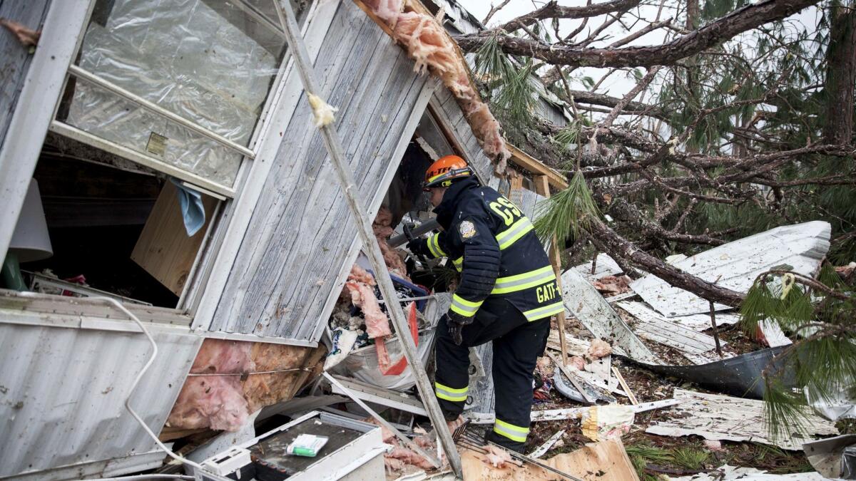 A rescue worker inspects a mobile home destroyed by a tornado in Albany, Ga.
