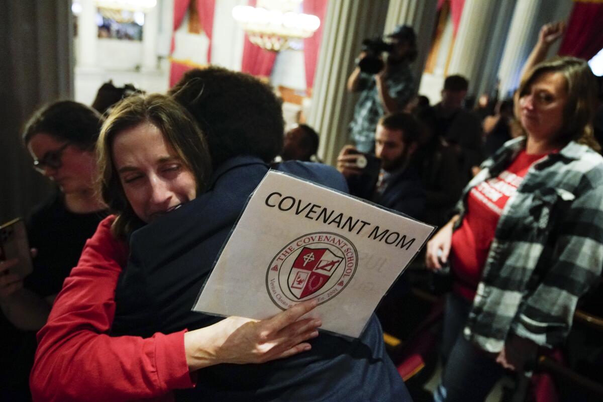 A woman with a sign that says "Covenant mom" hugs a man