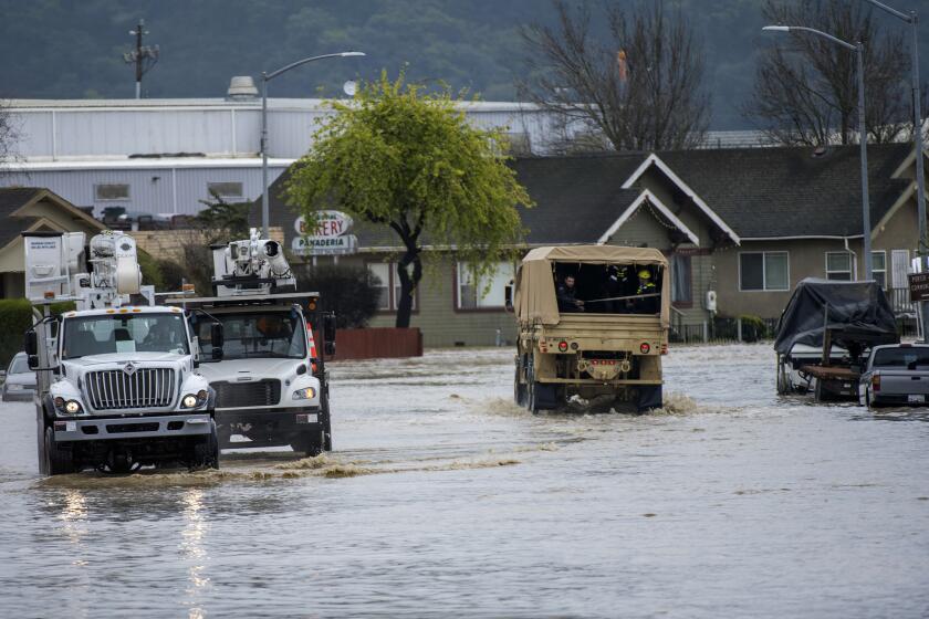 Utility vehicles and emergency personnel drove through floodwaters in Watsonville, Calif., Saturday, March 11, 2023. Gov. Gavin Newsom has declared emergencies in 34 counties in recent weeks, and the Biden administration approved a presidential disaster declaration for some on Friday morning, a move that will bring more federal assistance. (AP Photo/Nic Coury)