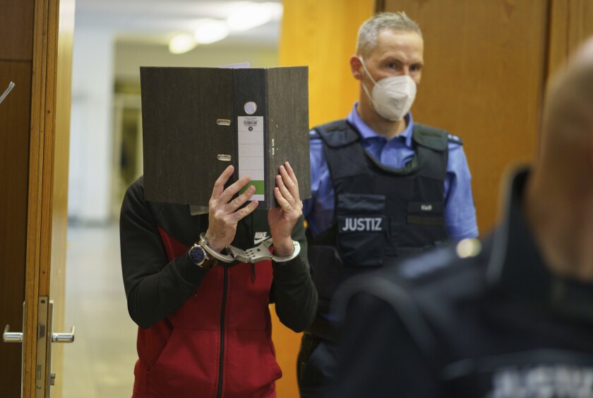 The Iraqi Taha Al-J. is led into the courtroom at Frankfurt's Higher Regional Court before the verdict is pronounced Frankfurt, Germany, Nov. 30, 2021. The Federal Prosecution accuses him of genocide, crimes against humanity, war crimes, human trafficking and murder. As a suspected member of the terrorist militia IS, he is alleged to have held a Yazidi woman and her daughter as slaves and abused them. In the process, he allegedly tied up the five-year-old in Fallujah, Iraq, where the child died of thirst in agony, according to the indictment. (Frank Rumpenhorst/Pool via AP)