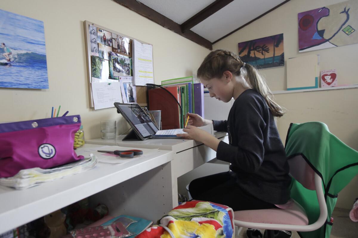 A student attends class via a laptop at her home in San Francisco.
