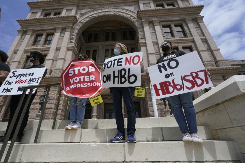 FILE - In this April 21, 2021, file photo, people opposed to Texas voter bills HB6 and SB7 hold signs during a news conference hosted by Texas Rising Action on the steps of the State Capitol in Austin, Texas. Republican lawmakers around the country are pressing ahead with efforts to tighten voting laws, despite growing warnings from business leaders that the measures could harm democracy and the economic climate. (AP Photo/Eric Gay, File)
