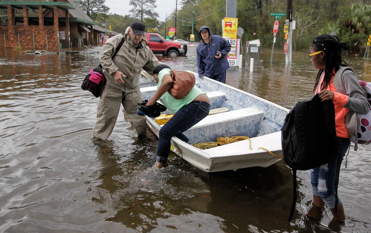 Shatripa Reid steps out of a boat after she and her daughter, Jamikka Rodgers, were picked up from their flooded home by Tangipahoa sheriff's deputies outside Hammond, La.