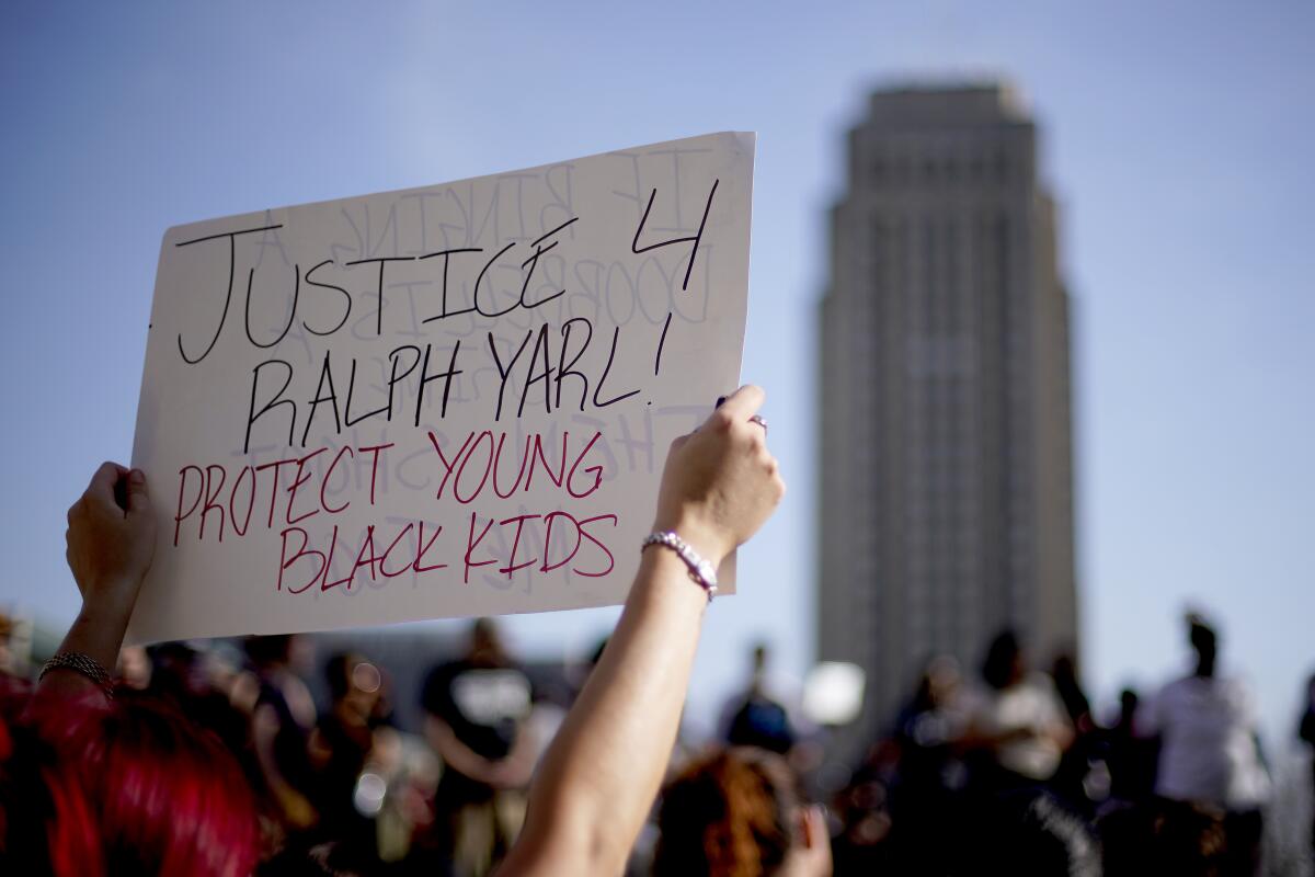 A protester in a crowd holds a sign that says "Justice 4 Ralph Yarl. Protect young Black kids."