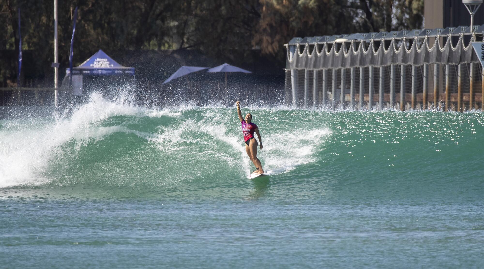 Johanne Defay raises her arm in victory while riding a wave