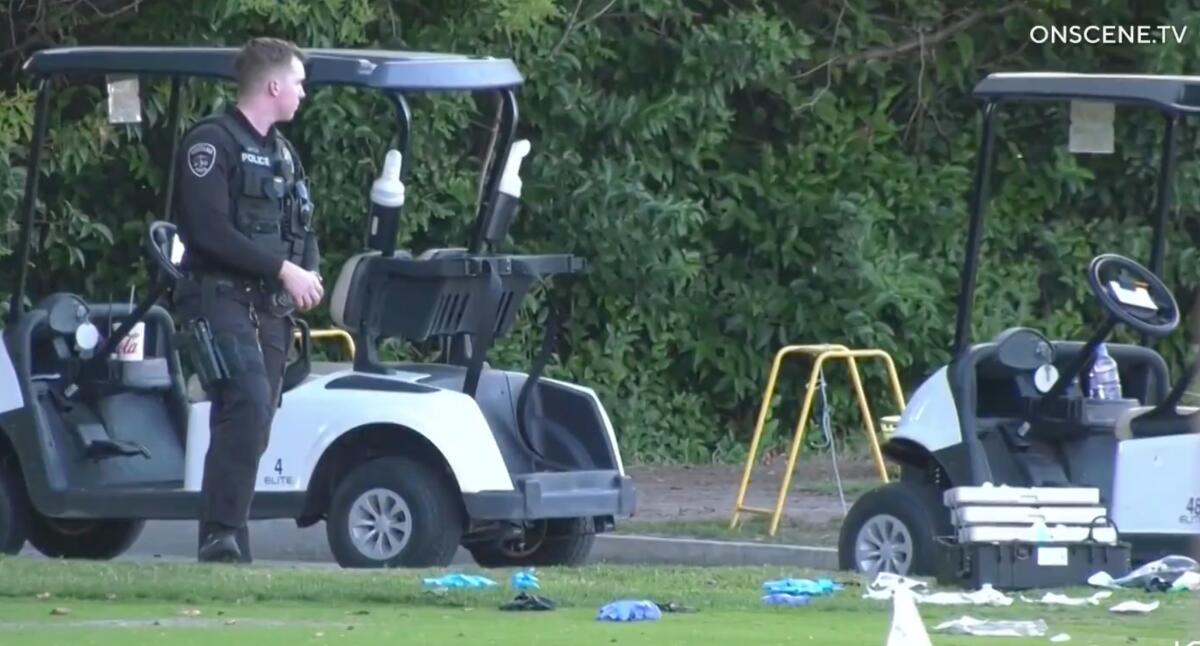 Police officers stand near golf carts at a shooting scene.