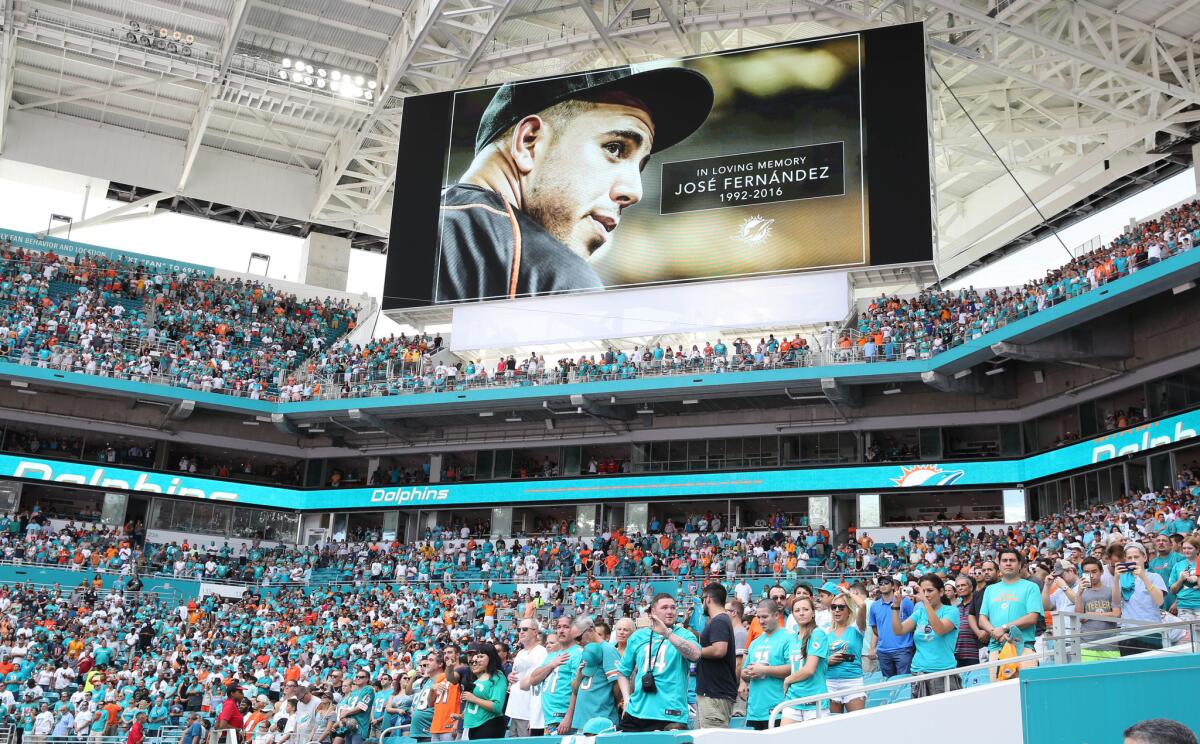 Miami Dolphins fans stand for a minute of silence for Miami Marlins pitcher Jose Fernandez, who was killed early Sunday, Sept. 25, 2016 in a boating accident in Miami. (AP Photo/Marta Lavandier)