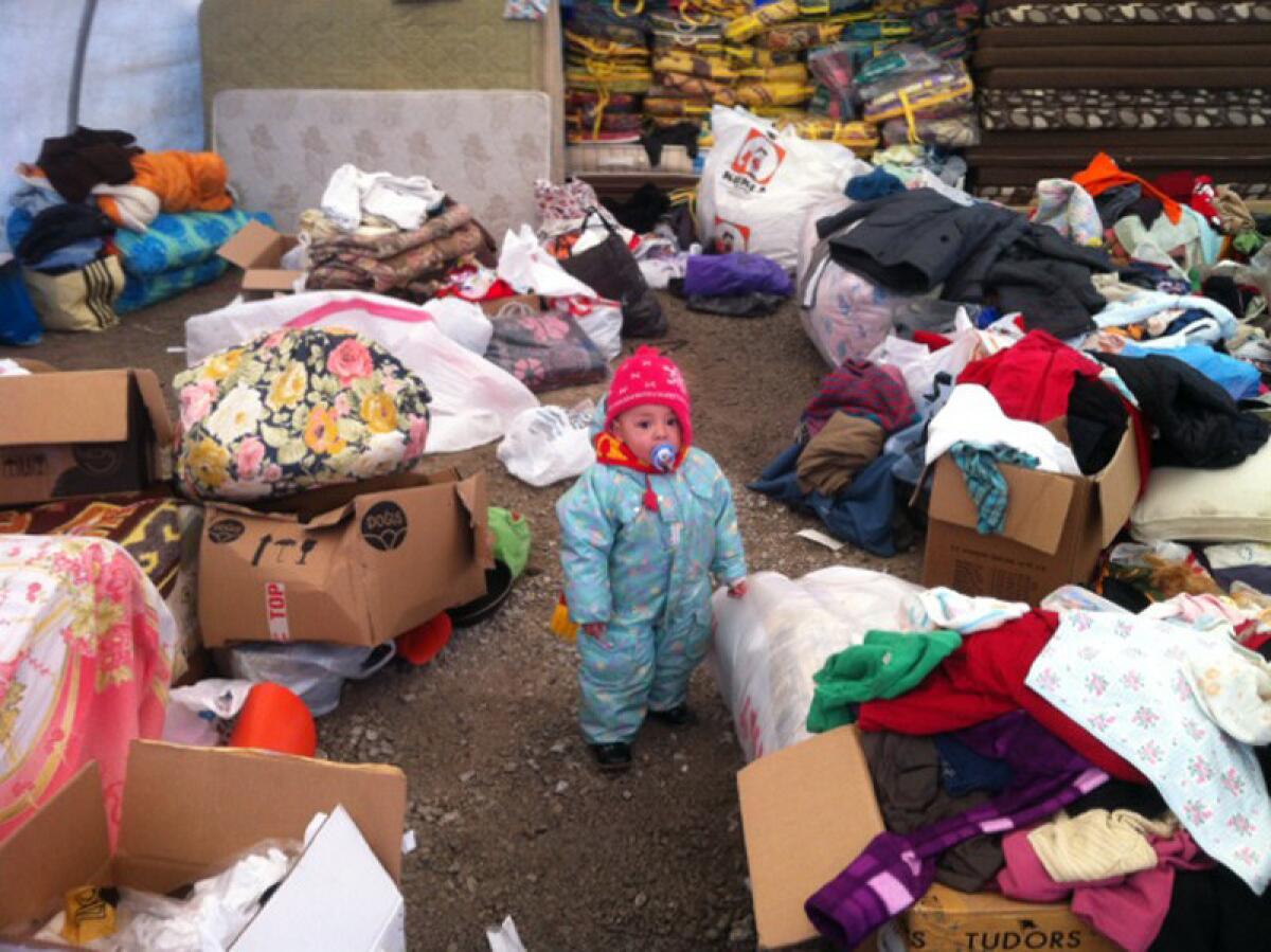 A child stands amid donated items for Uighur migrants in a tent in Kayseri, Turkey. More than 600 Uighurs from China are living in government-supplied apartments in the city, and residents have donated food, furniture and clothing for them.