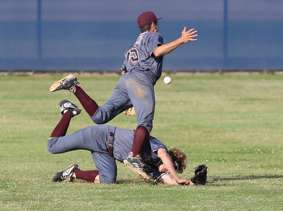 Laguna Beach High left fielder Will Potratz trips up shortstop Eric Silva (15) while trying to catch a short fly ball during a Wave League game at Newport Harbor on Friday.