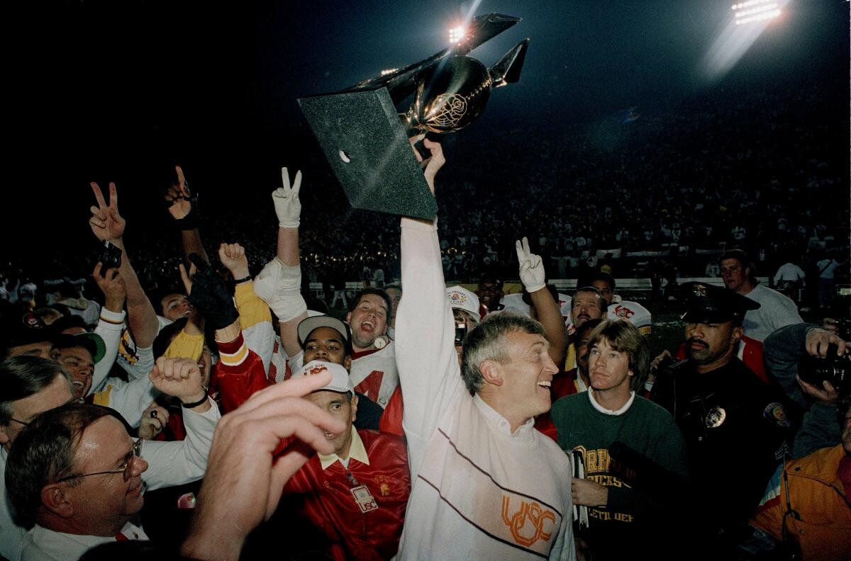 USC coach Larry Smith holds the Rose Bowl trophy over his head after a win over Michigan on Jan. 1, 1990.