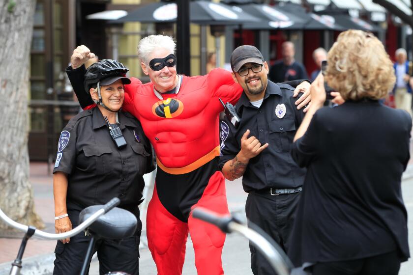SAN DIEGO, CA July 22nd, 2017 | Quentin marshall (middle), as Mr. Incredible, poses for a photo with Tammy Pierce (left) and Joshua Garcia on Saturday along 5th Avenue in the Gaslamp during the Comic-Con International Convention in San Diego, California. | (Eduardo Contreras / San Diego Union-Tribune)