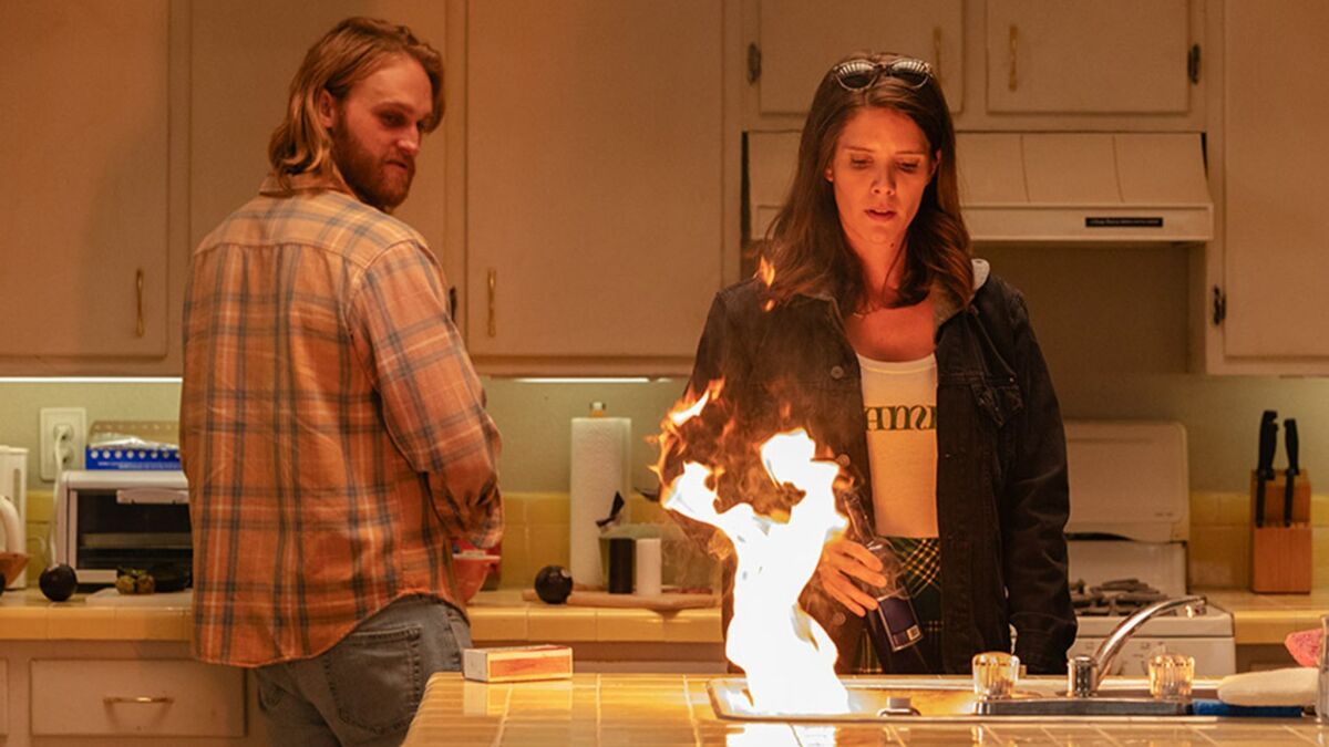 Wyatt Russell and Sonya Cassidy looking at a counter top fire in "Lodge 49."