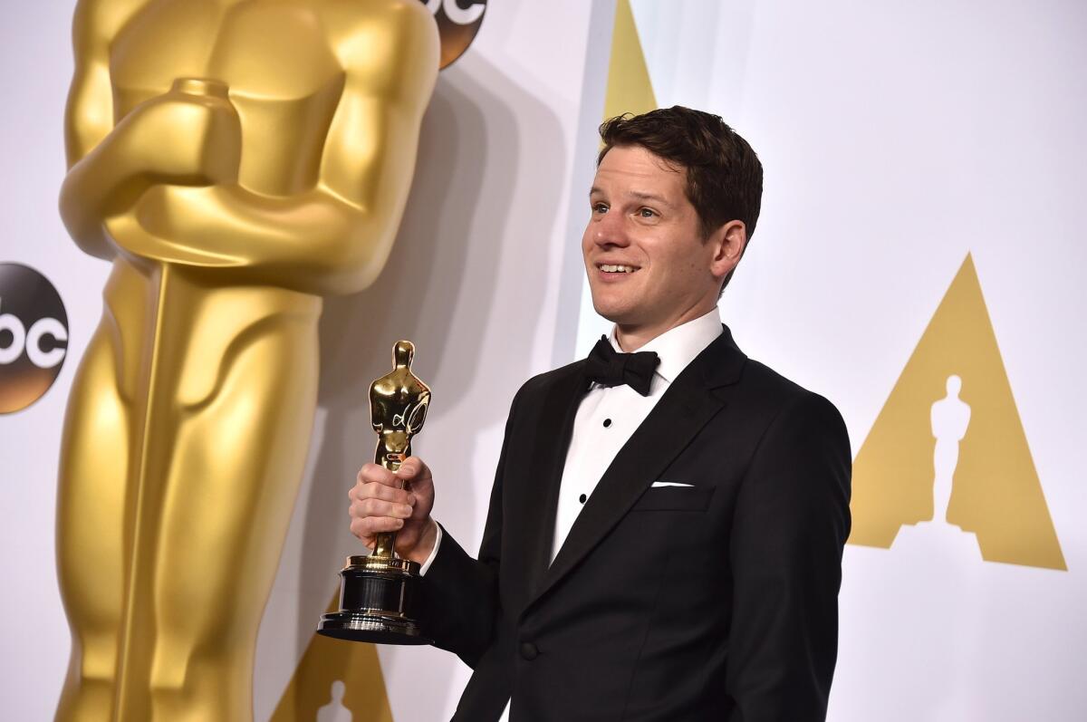 Graham Moore poses in the Oscars press room with his adapted screenplay trophy for "The Imitation Game."