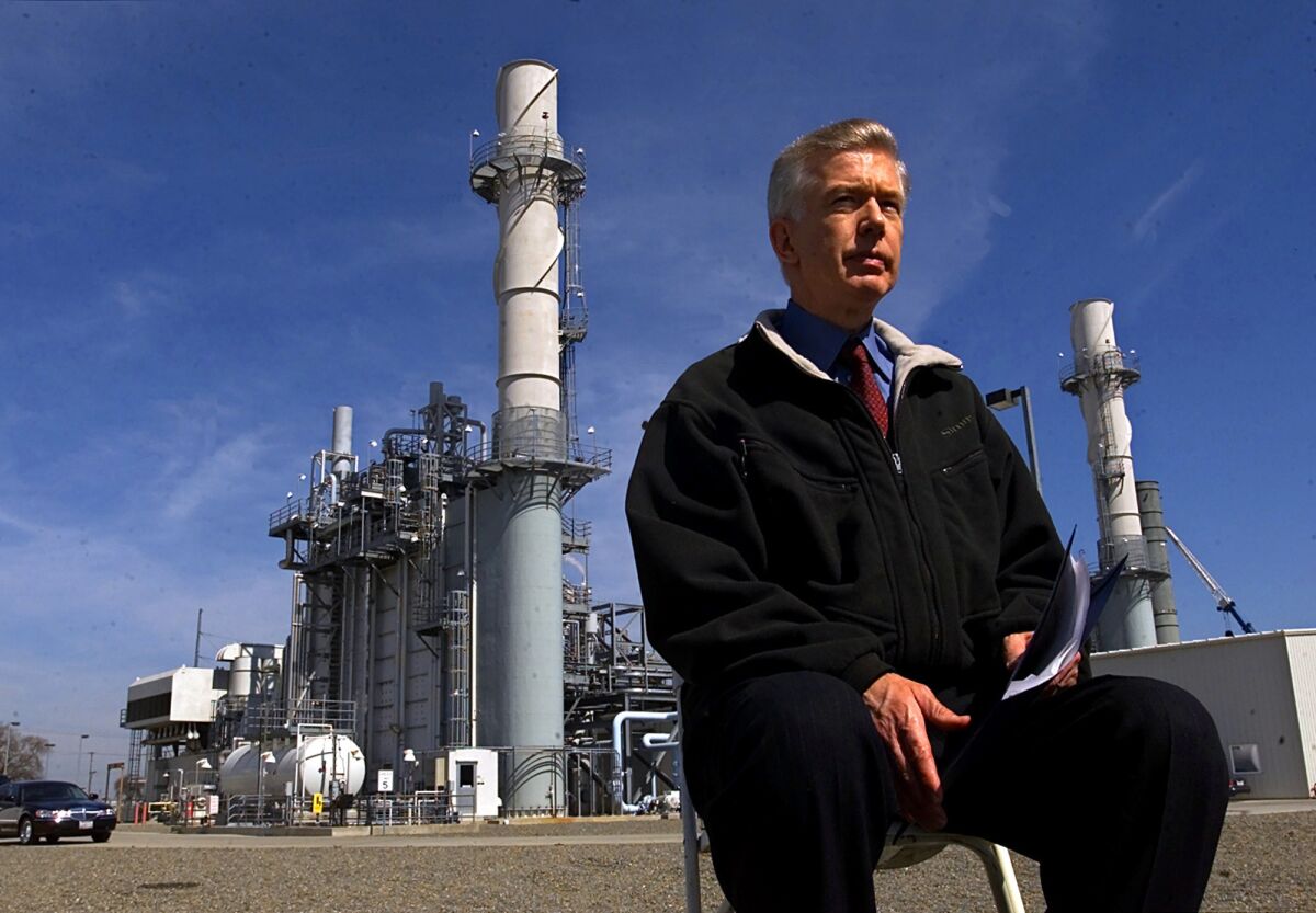A man sits in a chair outside at a power plant.