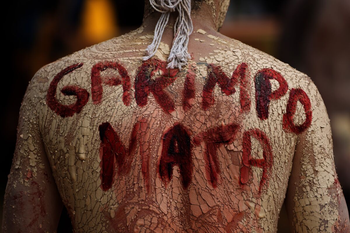FILE - An Indigenous man with the phrase painted on its back that reads in Portuguese "Mining Kills," participates in a protest against the increase of mining activities that are encroaching on his land, in front of the Ministry of Mines and Energy, in Brasilia, Brazil, Monday, April 11, 2022. A fast-expanding network of antennae is empowering Indigenous groups to use phones, video cameras and social media to galvanize the public and pressure authorities to respond swiftly to threats from gold miners, landgrabbers and loggers. (AP Photo/Eraldo Peres, File)