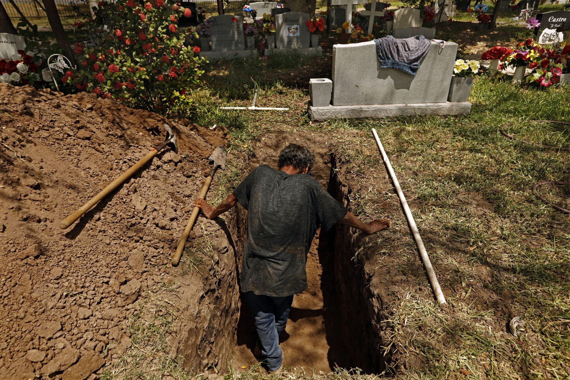 Jesus Torres, 75, digs a grave at La Piedad Cemetery in McAllen, Texas.