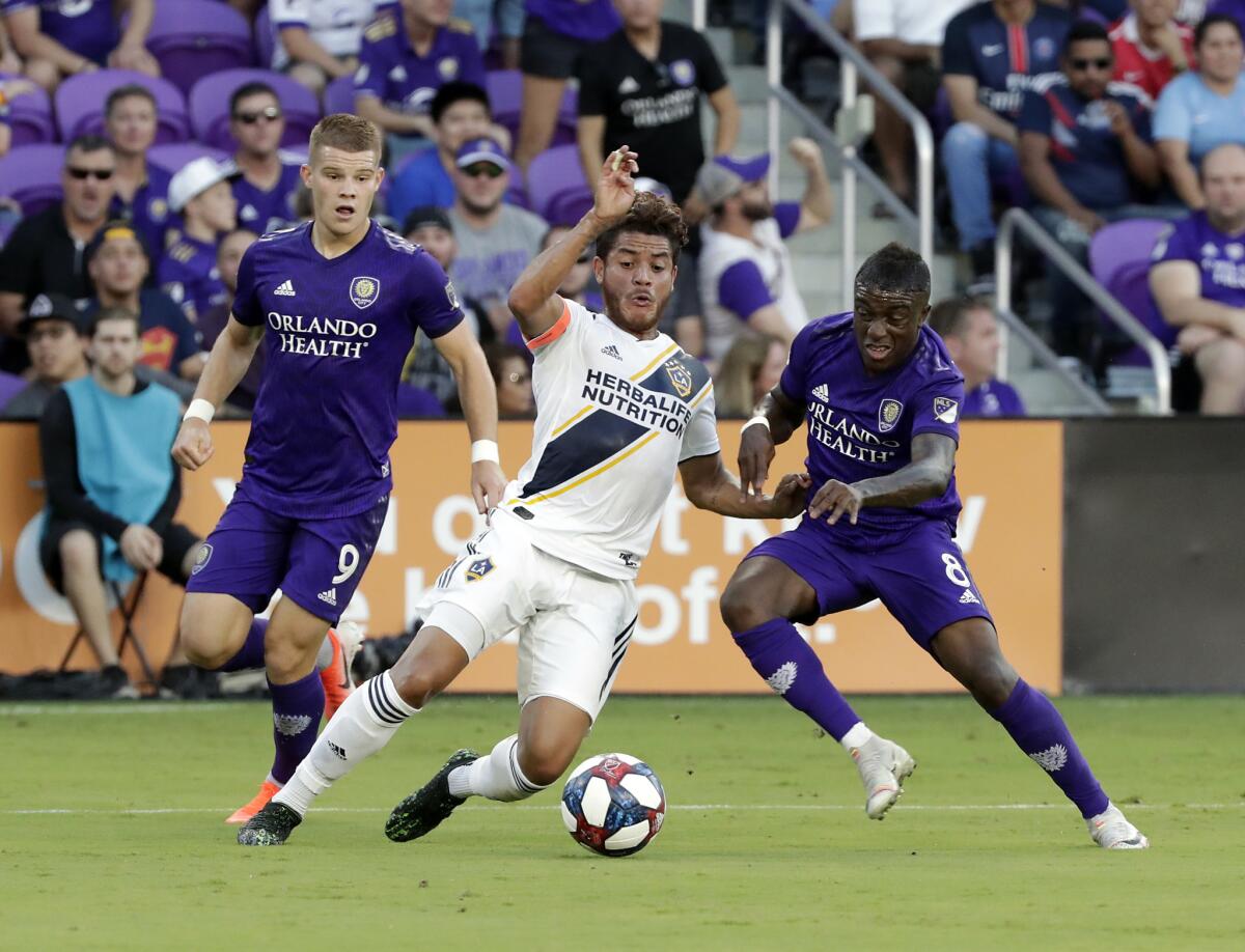 The Galaxy's Jonathan dos Santos, center, and Orlando City's Jhegson Sebastian Mendez, right, battle for possession as forward Chris Mueller watches May 24 in Orlando.