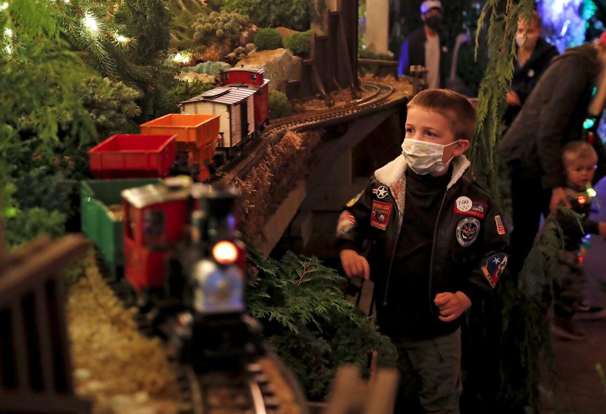 A youngster pauses to admire a holiday themed hobby train railway setup.