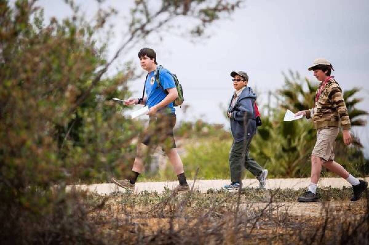 Jon Engstrom, 16, left, Luke Tomaneng, 11, and Jack Cotter look for a check point during an orienteering competition at Lake Balboa in Balboa Park in Encino.