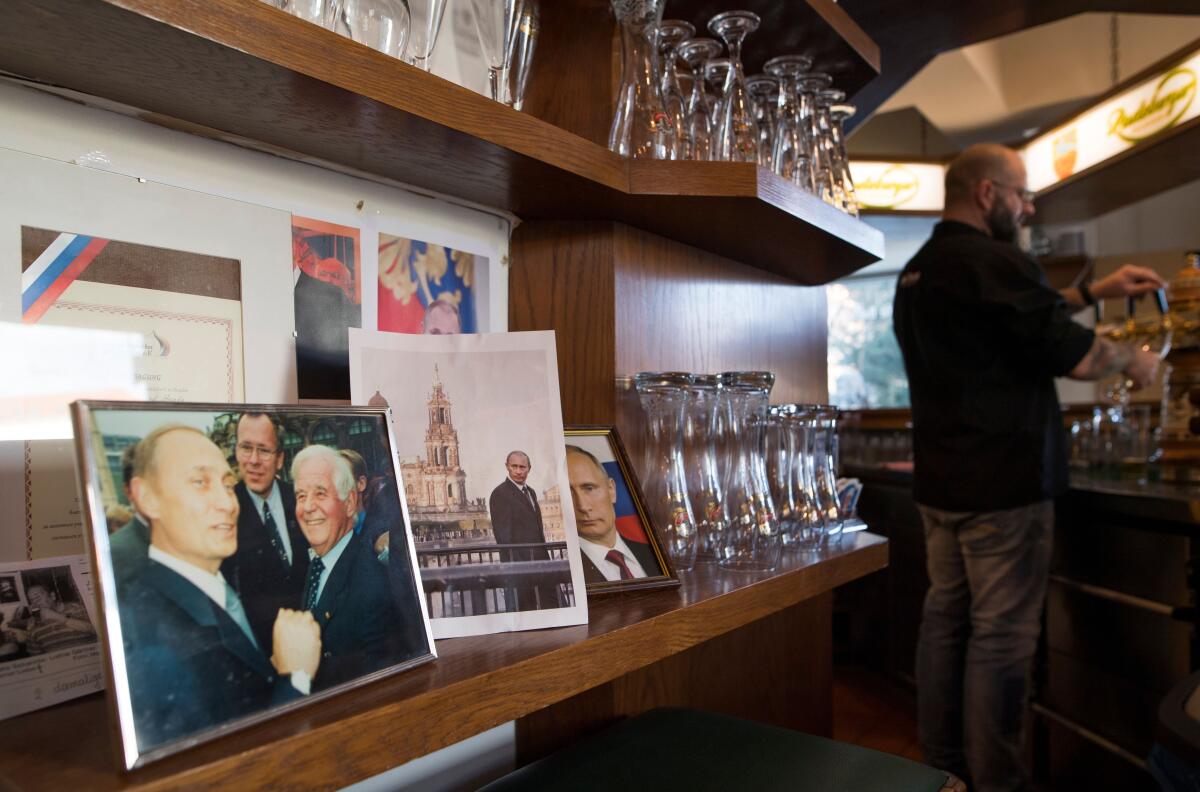 Photos of Vladimir Putin are displayed on a shelf at a German bar.