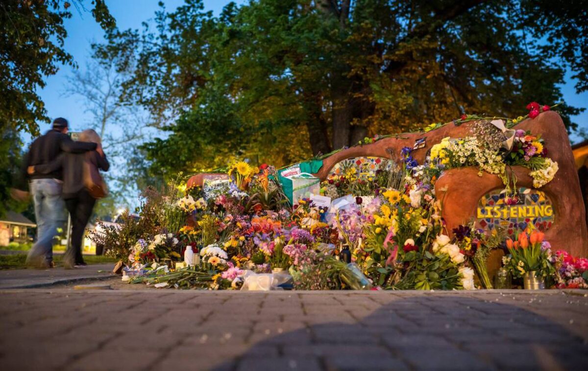 A couple walks by a Davis street bench decorated with tributes to David Breaux.