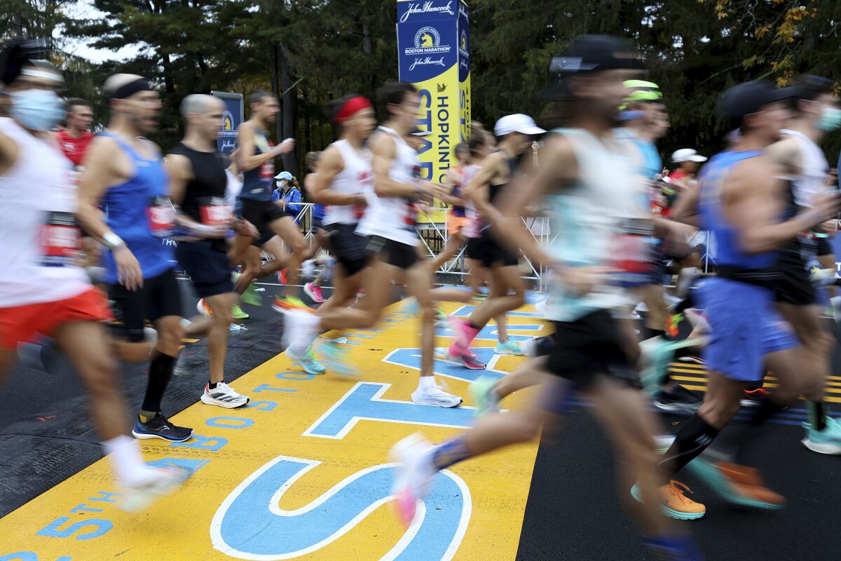 FILE - Runners cross the starting line of the 125th Boston Marathon, Monday, Oct. 11, 2021, in Hopkinton, Mass. The Boston Marathon returns, Monday, April 18, 2022. (AP Photo/Mary Schwalm, File)