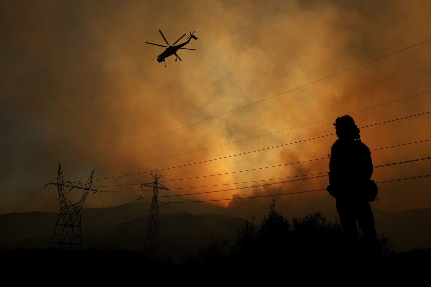 Fire Capt. Gus Munguia watches as a helicopter prepares to drop a load of water on the Powerhouse fire in Green Valley along San Francisquito Canyon Road.
