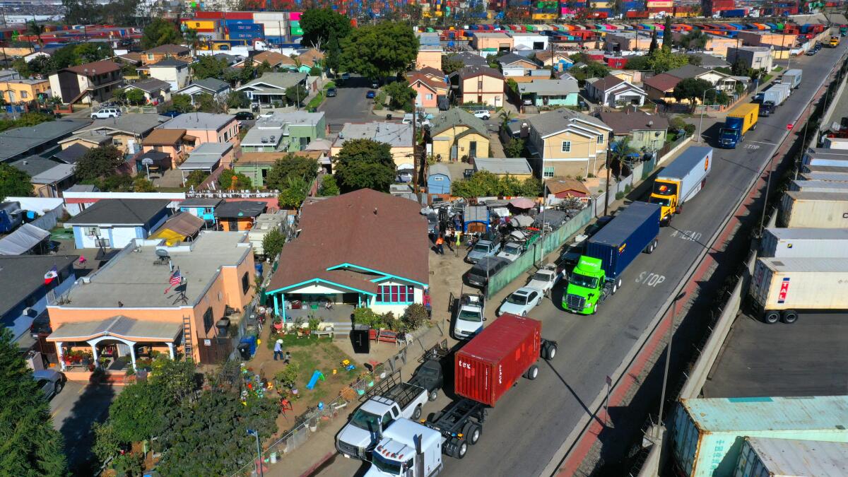 An aerial view of a dense neighborhood alongside a road that is packed with big rigs.