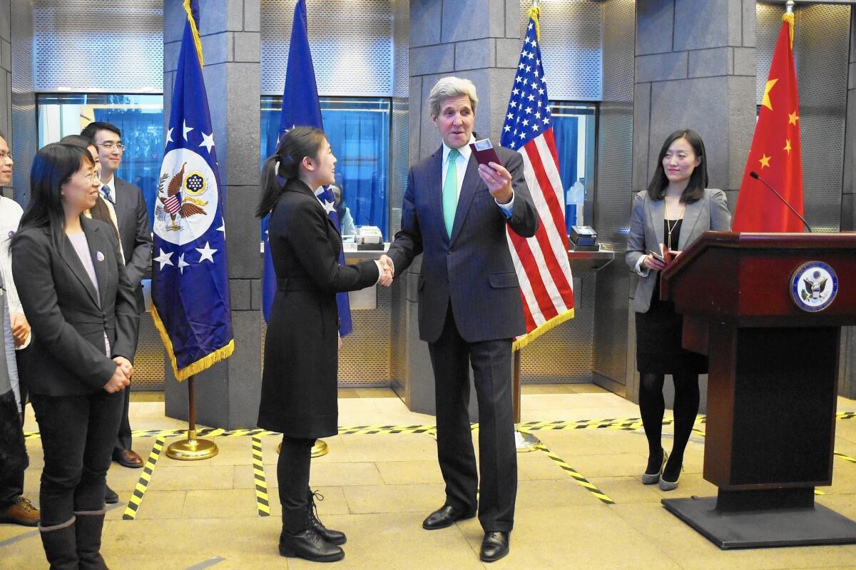 U.S. Secretary of State John Kerry prepares to give a visa to a Chinese woman at a press conference at the U.S. Embassy in Beijing.