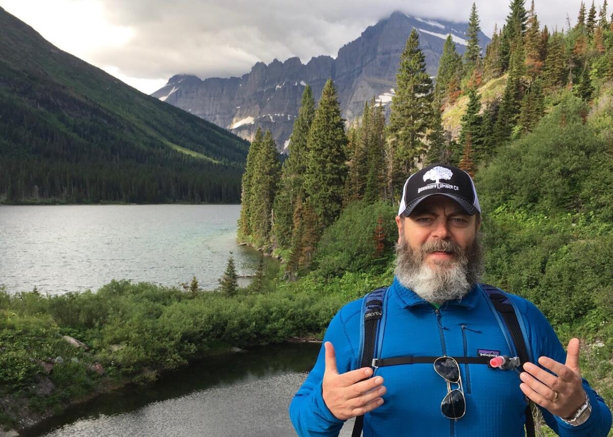 Nick Offerman, wearing outdoor gear, stands beside a mountain lake.