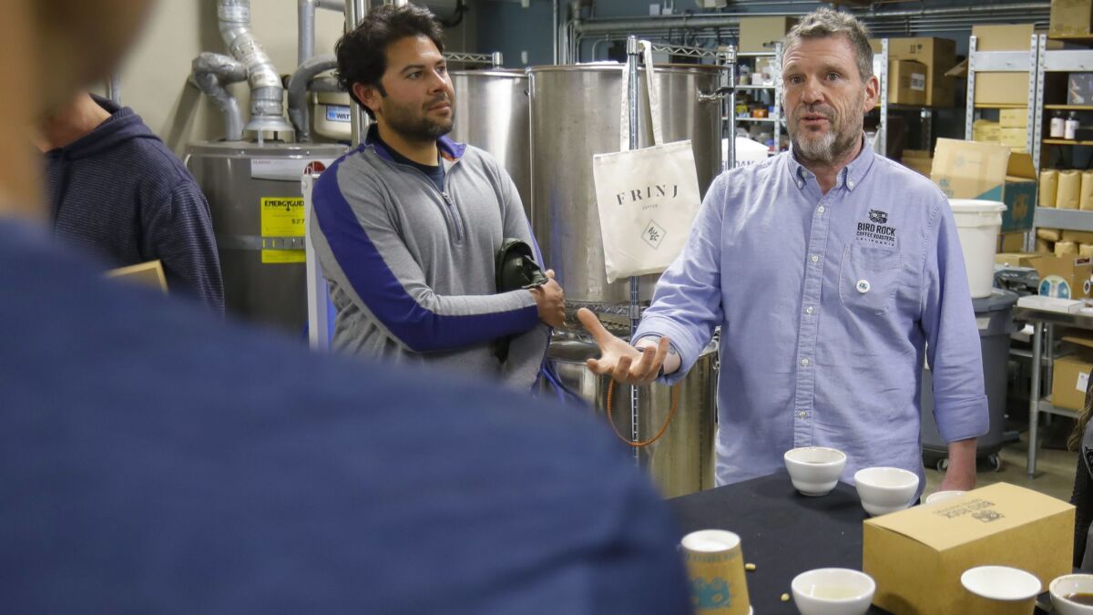 As customer Alex Holsheimer, center left, looks on, Bird Rock Coffee Roasters co-owner Jeffy Taylor talks about the Southern California-grown coffee beans they will be tasting on Saturday.
