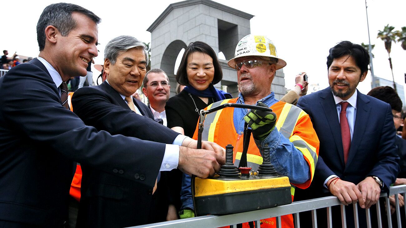 Los Angeles Mayor Eric Garcetti, left, and Yang Ho Cho, Chairman of Korean Air and the developer of the New Wilshire Grand project, push the switch on a remote control held by construction worker Mike Casad to activate the first pump during the start of the concrete pour. To the right of Cho is his daughter Heather, and at far right is State Senator Kevin De Leon.