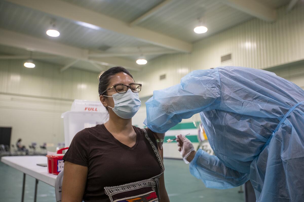 A person is administered a shot by a health worker in a gown