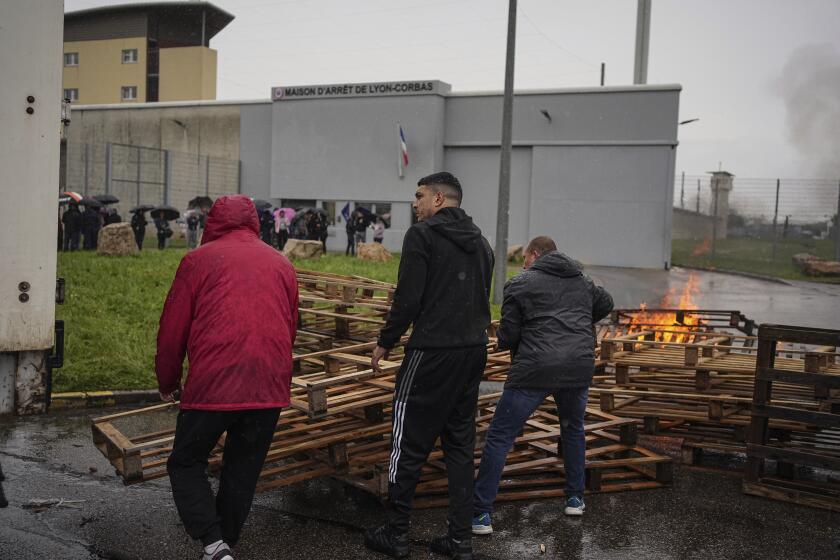 Prison workers burn wooden pallets during a protest in front of the Corbas prison, outside Lyon, France, Wednesday, May 15, 2024 . A massive manhunt was underway in France on Wednesday for an armed gang that ambushed a prison convoy, killing two prison officers, seriously injuring three others and springing the inmate they were escorting. (AP Photo/Laurent Cipriani)
