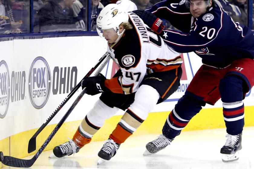 Ducks defenseman Hampus Lindholm tries to clear the puck while pressured by Blue Jackets winger Brandon Saad during their game Thursday night.
