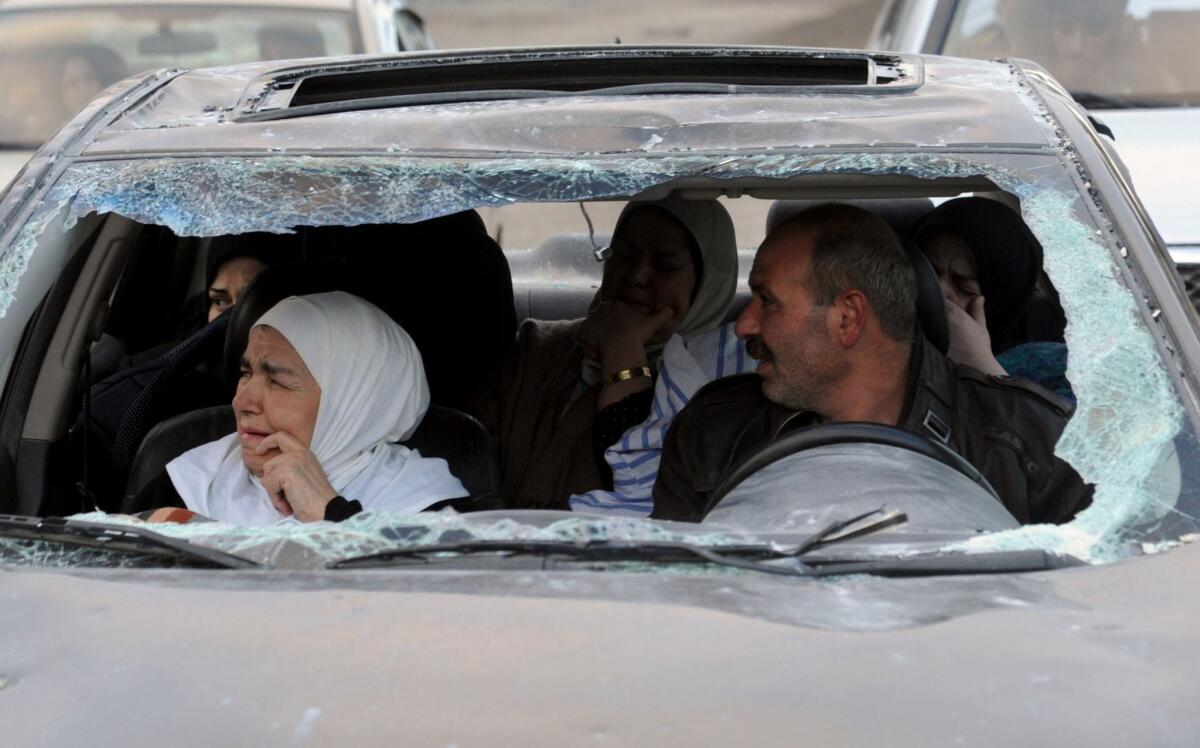 Syrians sit inside a damaged vehicle after forces loyal to President Bashar Assad's regime captured the town of Nabek, northeast of Damascus.
