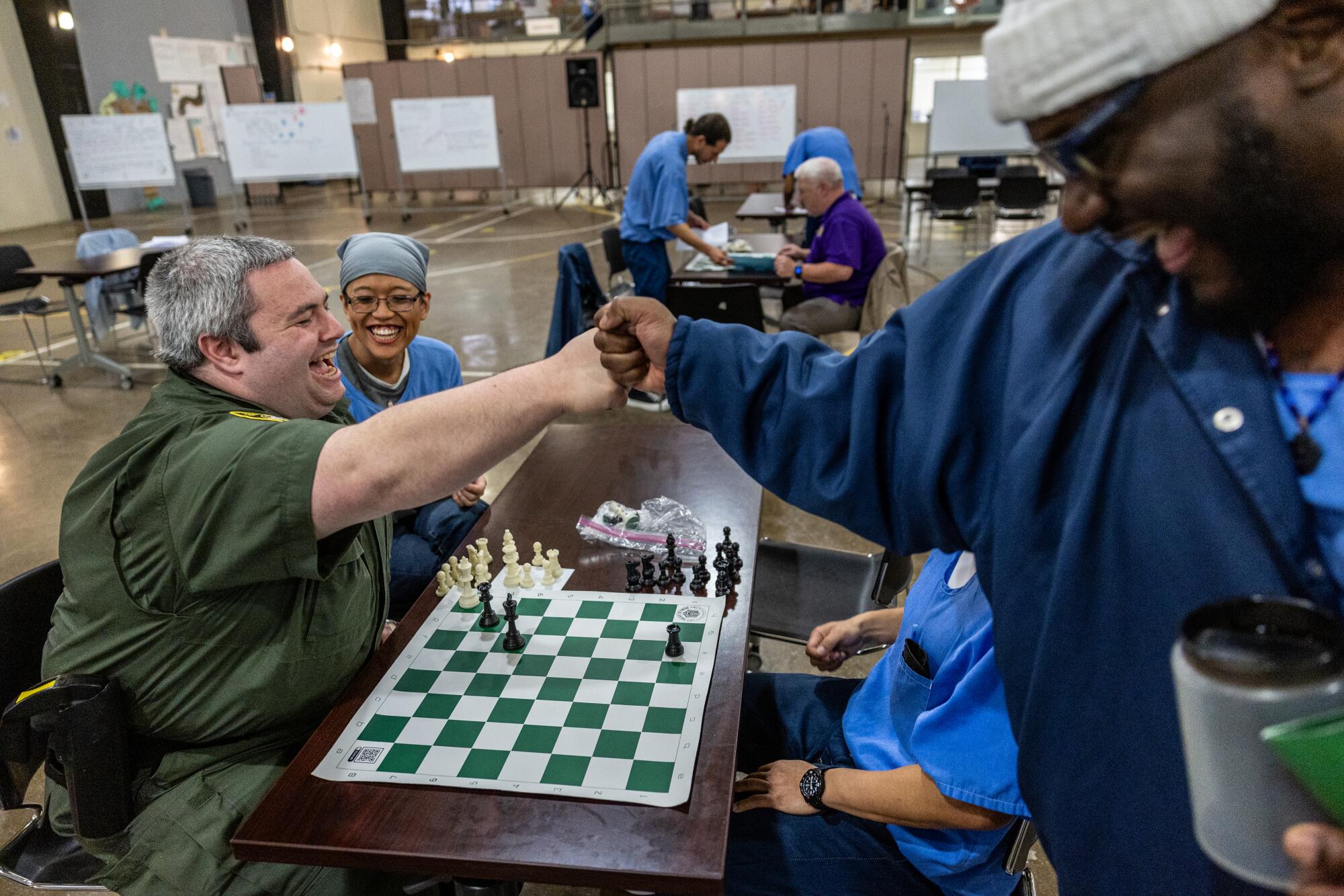 A prison guard fist-bumps a prisoner during a chess tournament 