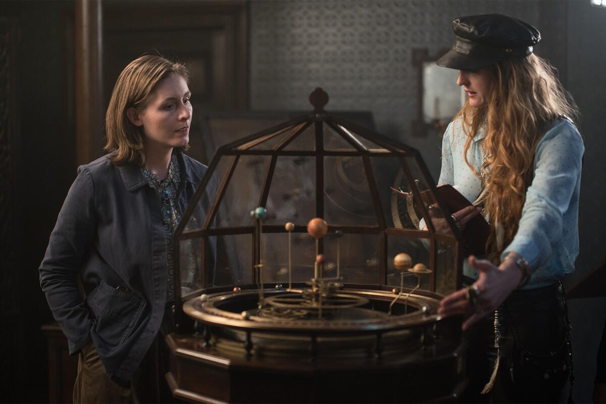 On "The Luminaries" set, author Eleanor Catton and director Claire McCarthy flank a model of the solar system.