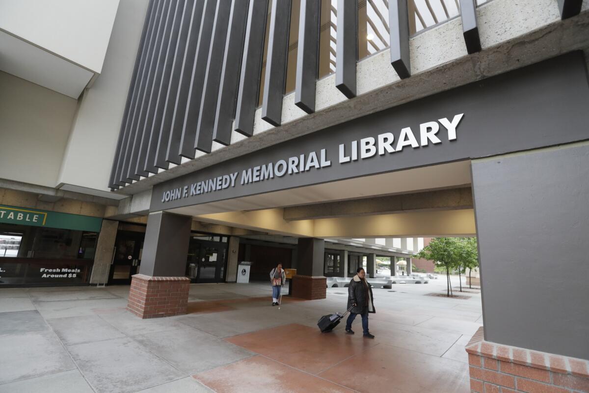 Students walk by the closed library on the campus of Cal State Los Angeles after L.A. County health officials issued one of the largest quarantine orders in state history.