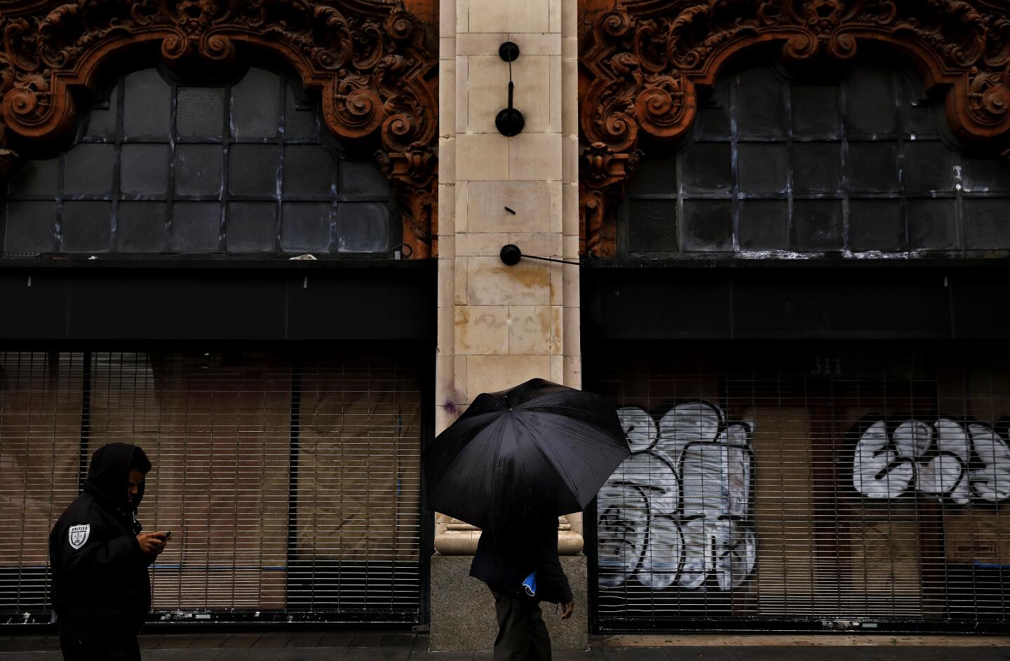 Pedestrians shield themselves from the rain in downtown Los Angeles.