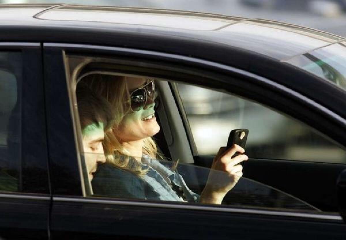 A motorist looks at her phone while behind the wheel in this 2010 photo.