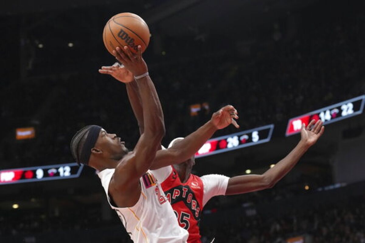 Miami Heat's Jimmy Butler, left, shoots on Toronto Raptors' Chris Boucher during the second half of an NBA basketball game in Toronto on Wednesday, Nov. 16, 2022. (Chris Young/The Canadian Press via AP)
