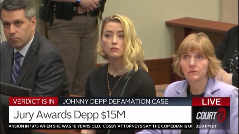 A screen grab of video shows a female defendant flanked by two attorneys