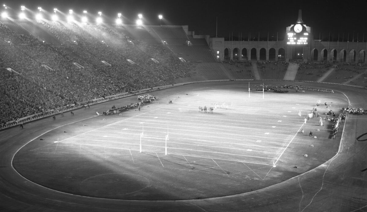 An overview of a stadium with fans in the seats and lights shining onto the field.