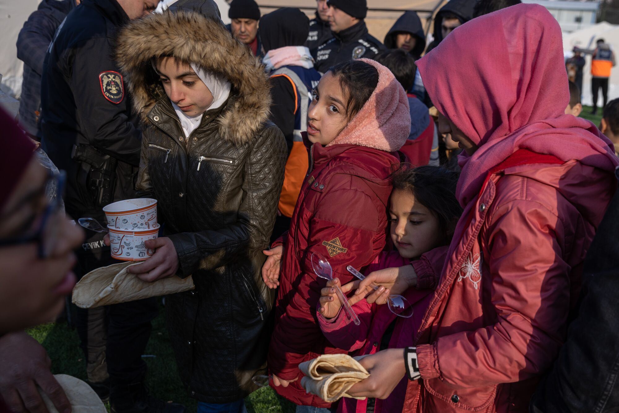 Yerinden edilmiş Suriyeliler, Türkiye'nin Kilis kenti yakınlarındaki bir spor merkezindeki derme çatma kampta yiyecek yardımı almak için bir araya geliyor.