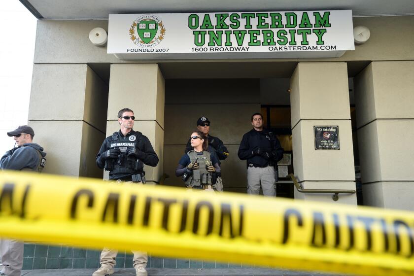 U.S. marshals stand at the entrance of Oaksterdam University in Oakland during a raid in 2012. The head of the university is pushing an initiative to legalize recreational use of marijuana for adults.