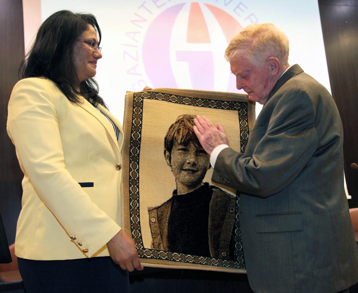 A man and a woman hold a portrait of a young boy.