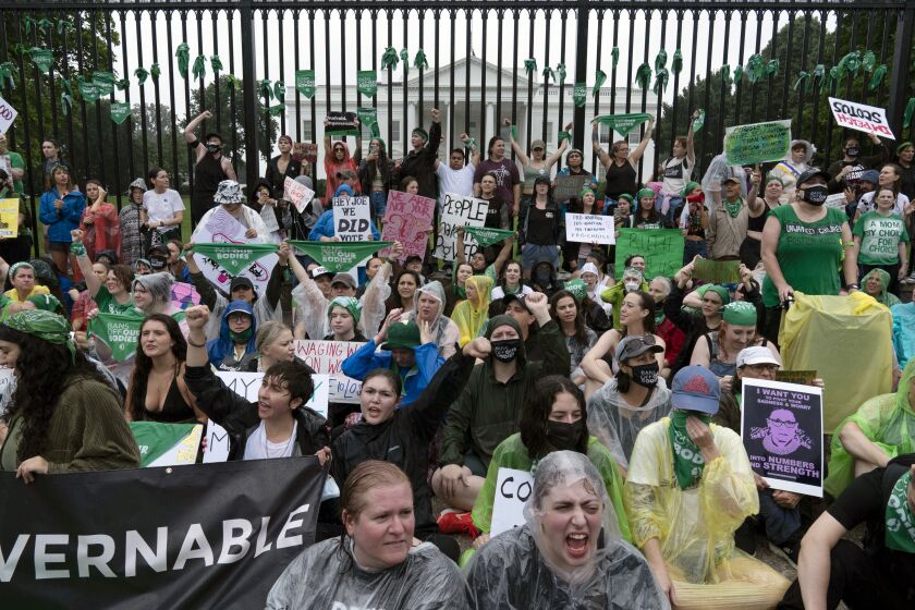 Abortion-rights demonstrators shout slogans after tying green flags to the fence of the White House during a protest to pressure the Biden administration to act and protect abortion rights, in Washington, Saturday, July 9, 2022. (AP Photo/Jose Luis Magana)