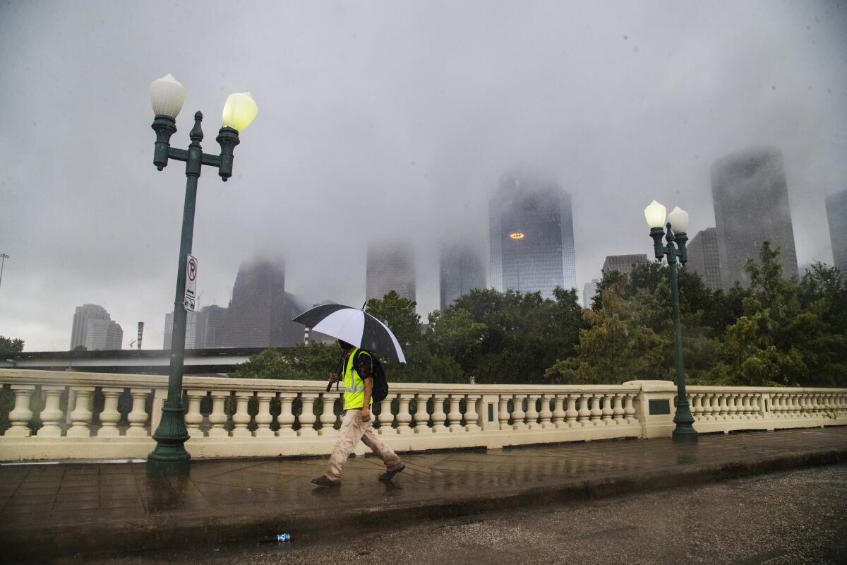 Un individuo camina bajo la lluvia con la silueta de Houston de fondo el 22 de septiembre del 2020. 